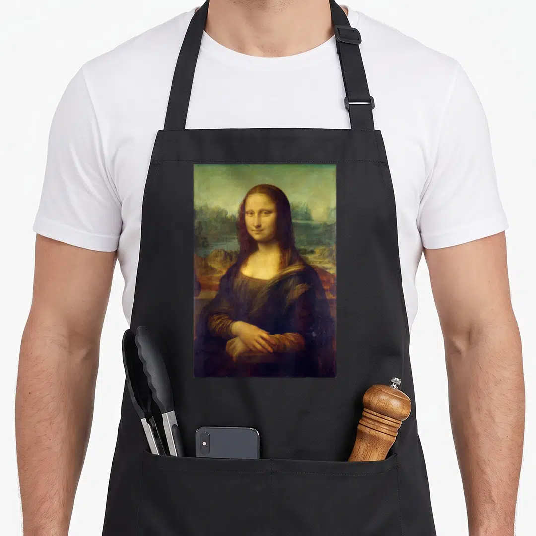Leonardo mona lisa apron - Portrait of a woman in dark clothing against a landscape background in brown and green tones — shown on a black cotton canvas apron against a white background