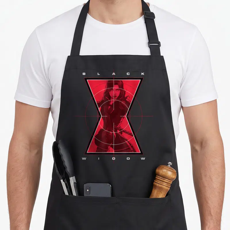 Cute target apron - Black Widow in red hourglass with crosshair, BLACK WIDOW text top and bottom — shown on a black cotton canvas apron against a white background