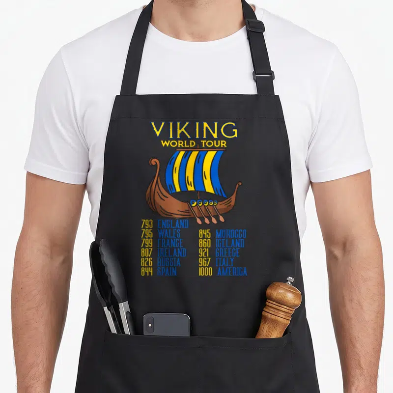 Viking swedish apron - Cartoon viking ship with blue yellow striped sail and two columns of dates and country names — shown on a black cotton canvas apron against a white background