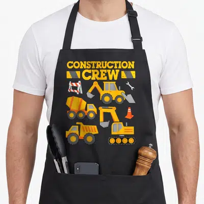 Crew construction worker apron - Cartoon excavator, cement mixer, and dump truck with CONSTRUCTION CREW text — shown on a black cotton canvas apron against a white background