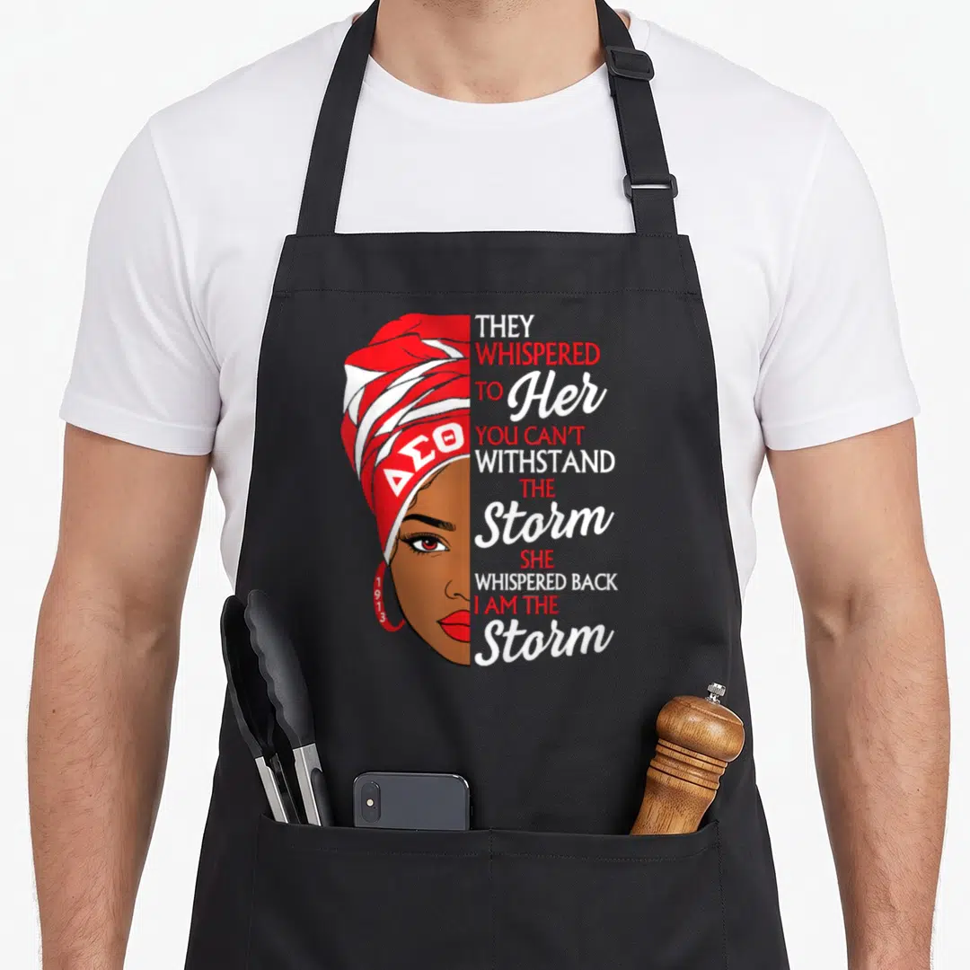 Theta sorority apron - Woman in red headwrap with DSO letters and stacked text reading They Whispered To Her You Can't — shown on a black cotton canvas apron against a white background