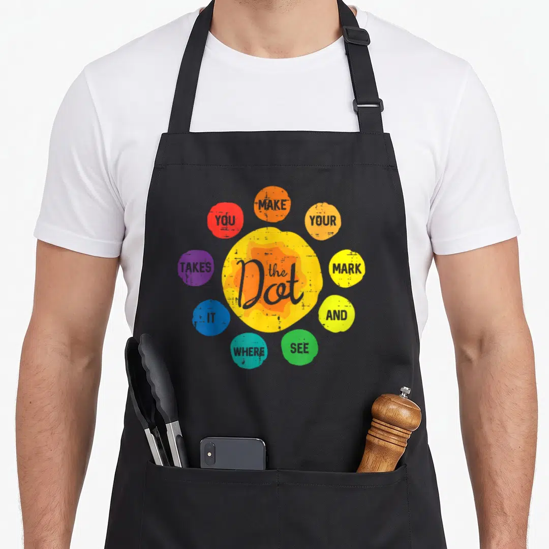 Toddler dot apron - Eight colorful circles surrounding a large orange and yellow dot with inspirational typography — shown on a black cotton canvas apron against a white background