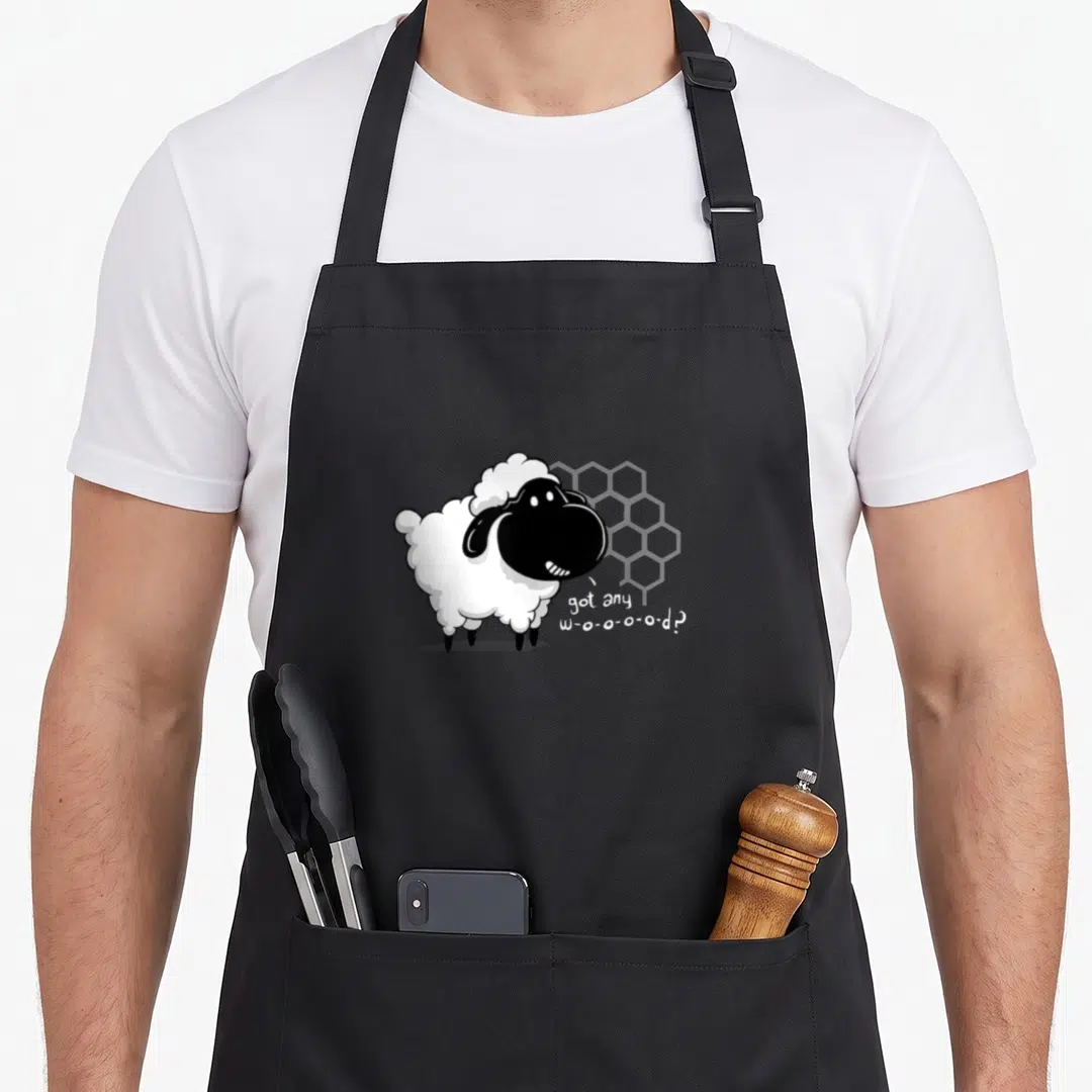 Board wood apron - Cartoon sheep with grey honeycomb and got any w-o-o-o-o-d text — shown on a black cotton canvas apron against a white background