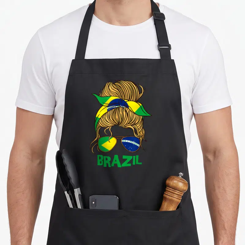 Brazil brazilian girl apron - Cartoon messy bun with Brazil flag headband, sunglasses showing DEM E PROGRES, and BRAZIL — shown on a black cotton canvas apron against a white background
