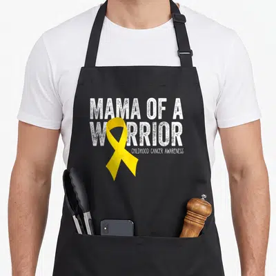 Warrior mama apron - Yellow ribbon overlapping distressed white MAMA OF A WARRIOR text — shown on a black cotton canvas apron against a white background