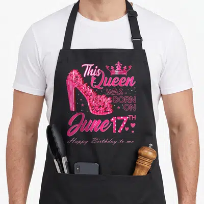 Heel 17th birthday apron - Pink high heel shoe with This Queen WAS BORN ON June 17TH text — shown on a black cotton canvas apron against a white background