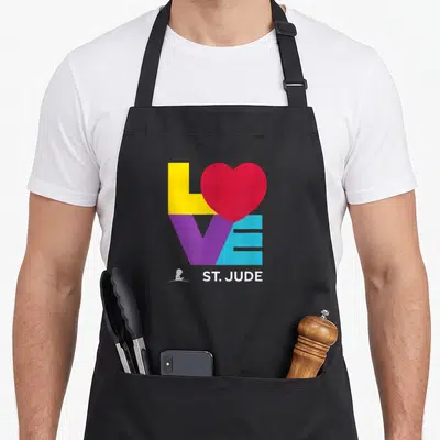 Research hospital apron - Colorful LOVE text with red heart and white St Jude logo — shown on a black cotton canvas apron against a white background