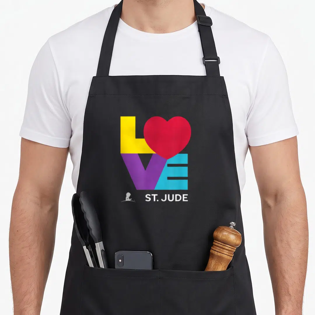 Research hospital apron - Colorful LOVE text with red heart and white St Jude logo — shown on a black cotton canvas apron against a white background
