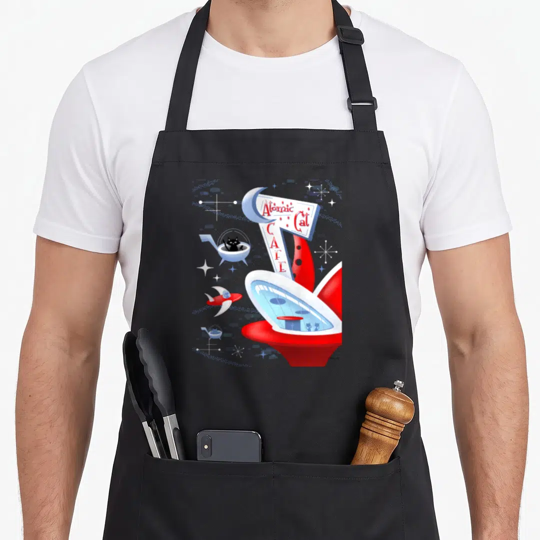 Cafe cat apron - Retro Atomic Cat Cafe sign with black cat in space pod and starburst graphics — shown on a black cotton canvas apron against a white background