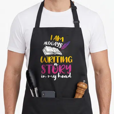 Book publisher apron - I AM ALWAYS WRITING a STORY in my head text with open book and purple feather — shown on a black cotton canvas apron against a white background