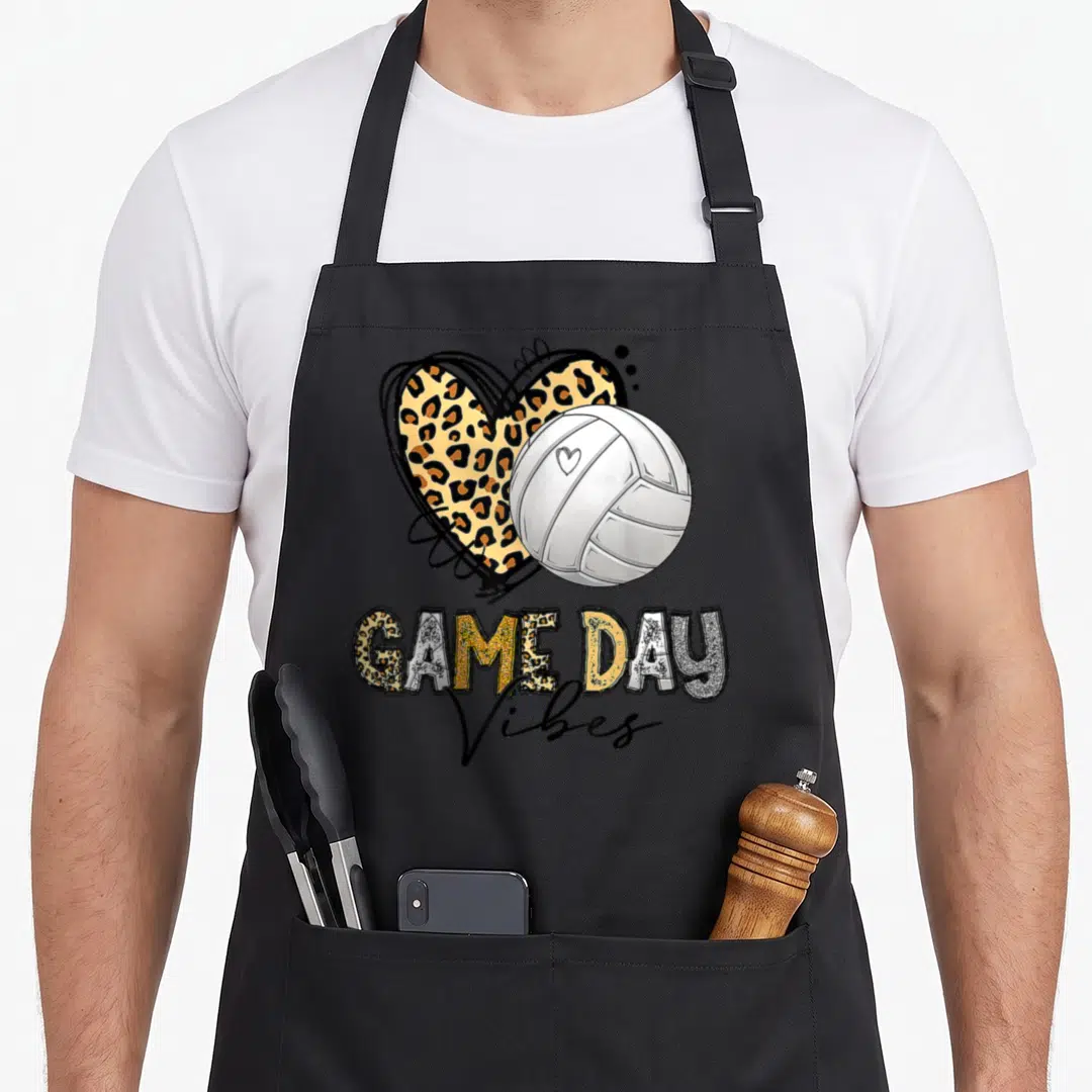 Bleached leopard apron - Volleyball overlapping leopard heart with GAME DAY Vibes text in gold and silver — shown on a black cotton canvas apron against a white background