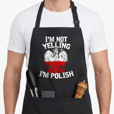 Yelling polish aprons - Distressed white and red eagle centered between I'm Not Yelling I'm Polish text — shown on a black cotton canvas apron against a white background