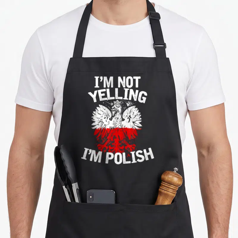 Yelling polish aprons - Distressed white and red eagle centered between I'm Not Yelling I'm Polish text — shown on a black cotton canvas apron against a white background
