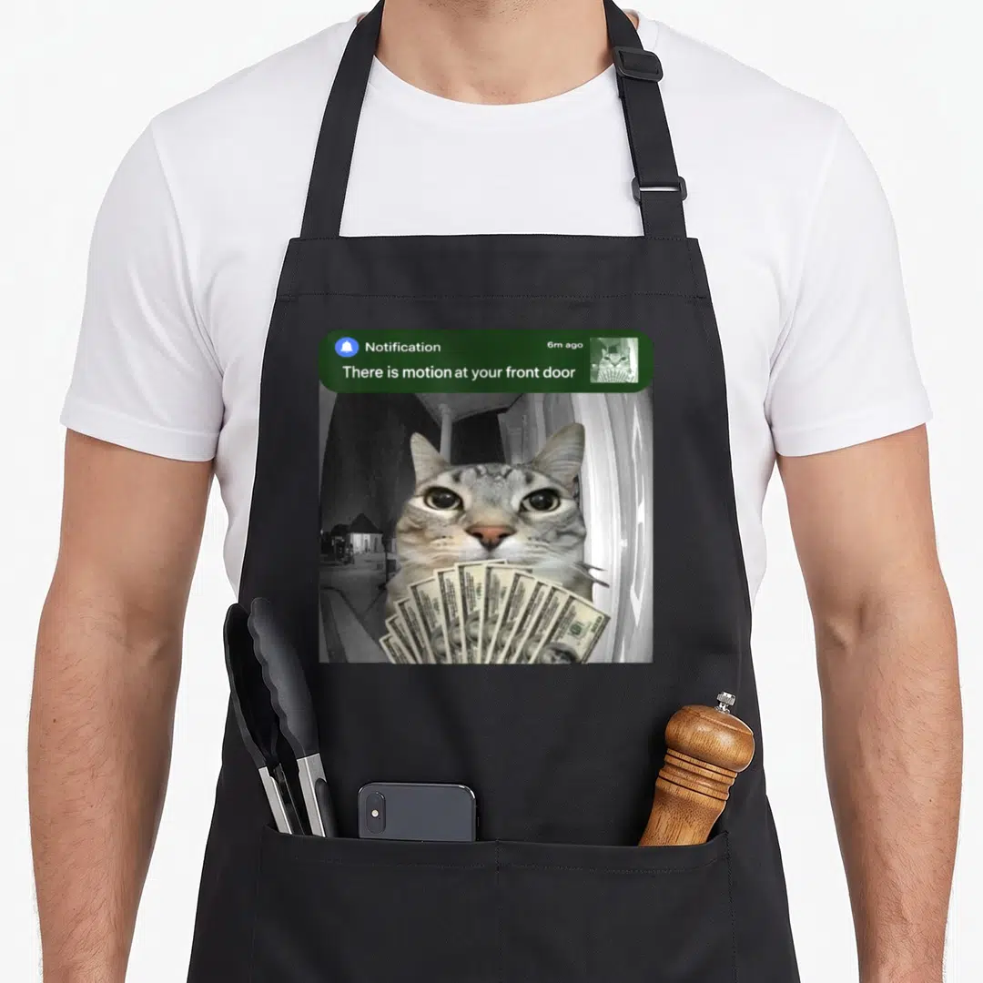 Motion front door apron - Cat holding fan of dollar bills under green notification banner with white text — shown on a black cotton canvas apron against a white background