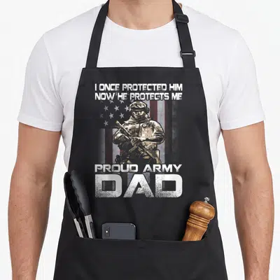 Once army apron - Soldier holding rifle before faded US flag with text I ONCE PROTECTED HIM NOW HE PROTECTS ME PROUD — shown on a black cotton canvas apron against a white background
