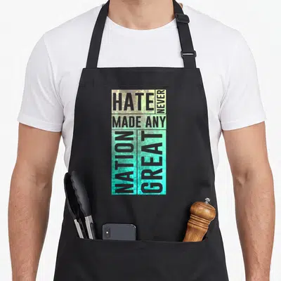 Immigrant pro apron - Stacked grey text reading Hate Never Made Any Nation Great on teal and yellow background — shown on a black cotton canvas apron against a white background