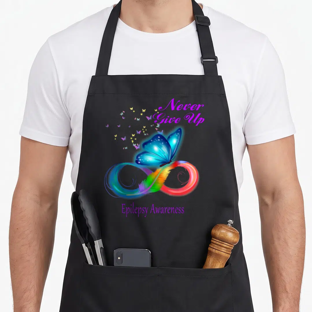 Epilepsy awareness butterfly apron - Blue butterfly on rainbow infinity symbol with purple Never Give Up text — shown on a black cotton canvas apron against a white background