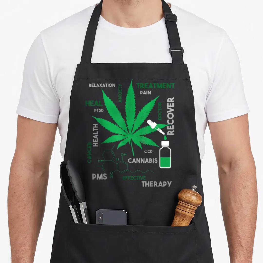 Cbd hemp apron - Green cannabis leaf surrounded by medical terms like treatment and pain with a dropper and chemical — shown on a black cotton canvas apron against a white background