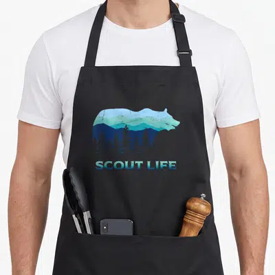 Scout camping apron - Bear silhouette containing blue mountains and pine trees with SCOUT LIFE text below — shown on a black cotton canvas apron against a white background