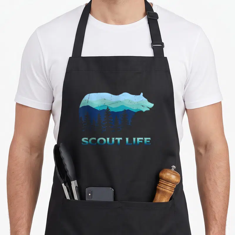 Scout camping apron - Bear silhouette containing blue mountains and pine trees with SCOUT LIFE text below — shown on a black cotton canvas apron against a white background