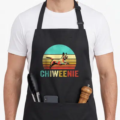 Chiweenie dog apron - Retro jumping dog in front of multi-colored semi-circle with CHIWEENIE text below — shown on a black cotton canvas apron against a white background
