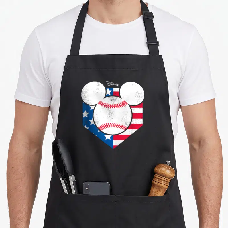 Funny diamond baseball apron - Mickey head silhouette filled with baseball over distressed US and Texas flags — shown on a black cotton canvas apron against a white background