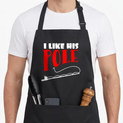 Pole couple apron - I LIKE HIS POLE text in red and white above fishing rod line art — shown on a black cotton canvas apron against a white background