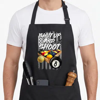 Shut billiards apron - SHUT UP AND SHOOT text over grayscale flag and wooden billiard ball tray with 8-ball — shown on a black cotton canvas apron against a white background