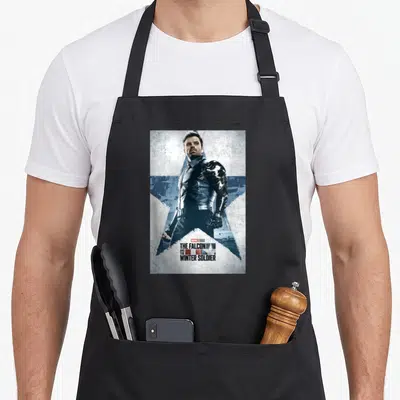 Bucky falcon apron - Man in black leather standing before blue and white star with stacked title text — shown on a black cotton canvas apron against a white background