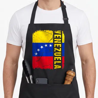 Venezuelan flag pride apron - Distressed Venezuelan flag with yellow blue red stripes and vertical VENEZUELA text — shown on a black cotton canvas apron against a white background