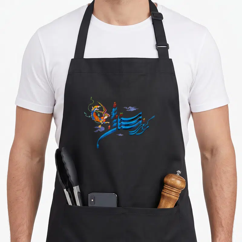 Mastaneh unique apron - Realistic angel in orange blue yellow beside large blue 3D calligraphy with small scattered — shown on a black cotton canvas apron against a white background