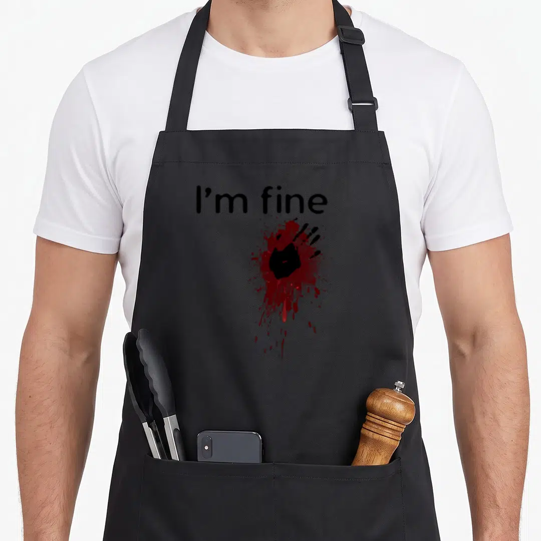 Splatter halloween apron - I'm fine text above red blood splatter and black hand print graphic — shown on a black cotton canvas apron against a white background