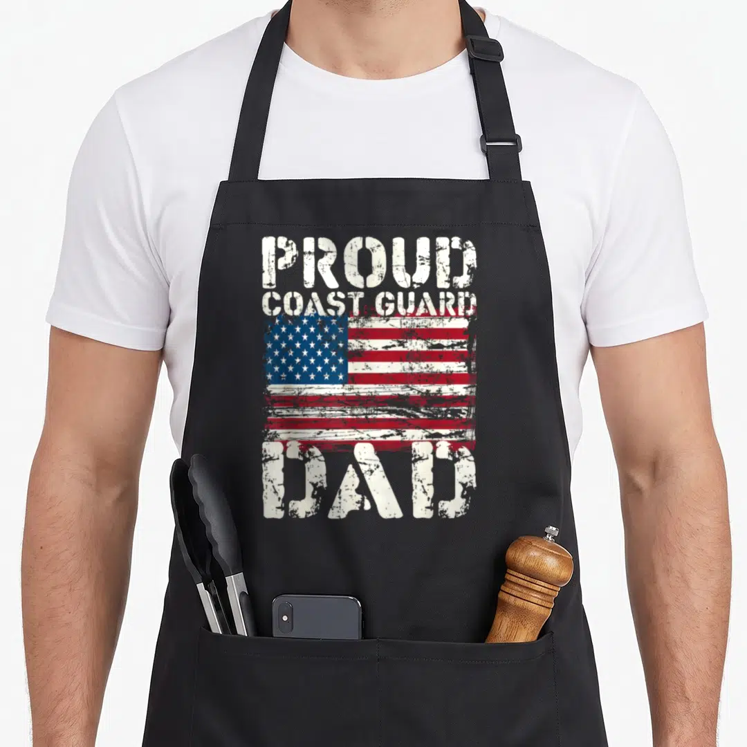 Uscg american flag apron - Distressed USA flag with PROUD COAST GUARD DAD text in white red and blue — shown on a black cotton canvas apron against a white background