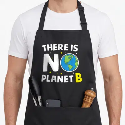 Planet young wild apron - Cartoon Earth replaces O in white text reading There Is No Planet B with yellow stars — shown on a black cotton canvas apron against a white background