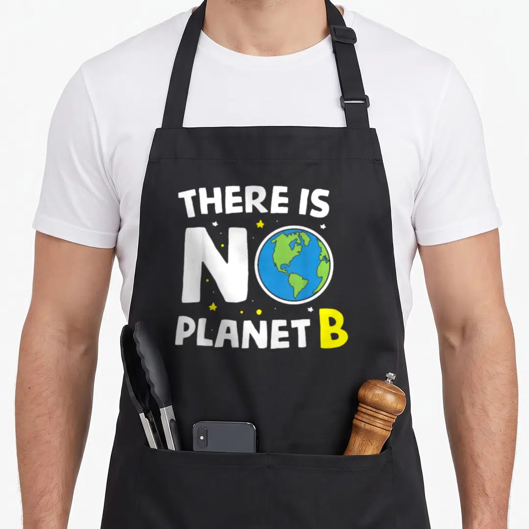 Planet young wild apron - Cartoon Earth replaces O in white text reading There Is No Planet B with yellow stars — shown on a black cotton canvas apron against a white background