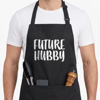 Hubby wedding apron - White distressed typography reading FUTURE HUBBY stacked vertically on grey background — shown on a black cotton canvas apron against a white background