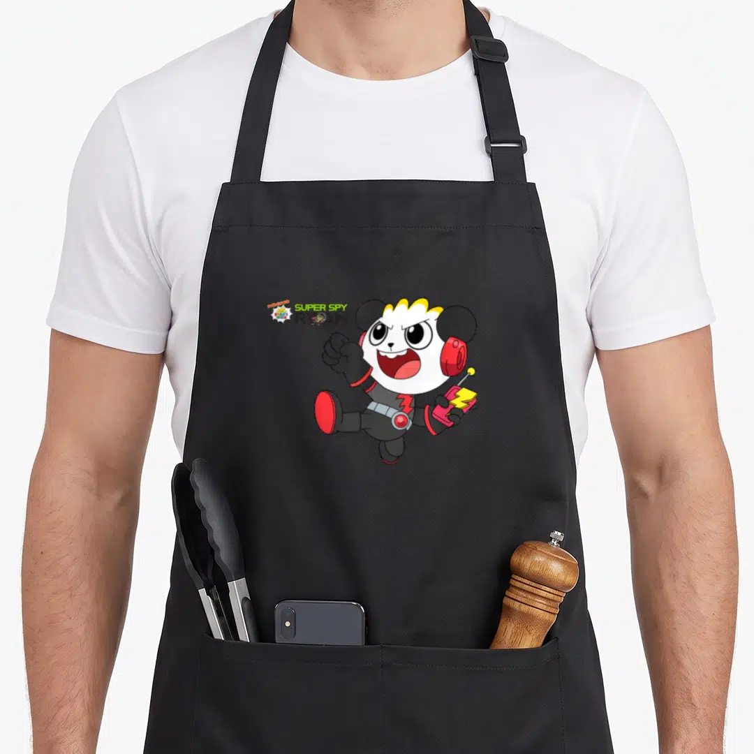 Ryan panda apron - Running cartoon panda spy holding red device next to SUPER SPY RYAN text — shown on a black cotton canvas apron against a white background