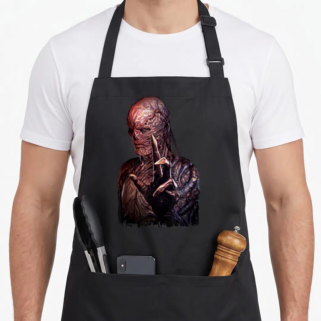Vecna hand apron - Realistic monster portrait with raised hand in brown and dark red tones — shown on a black cotton canvas apron against a white background