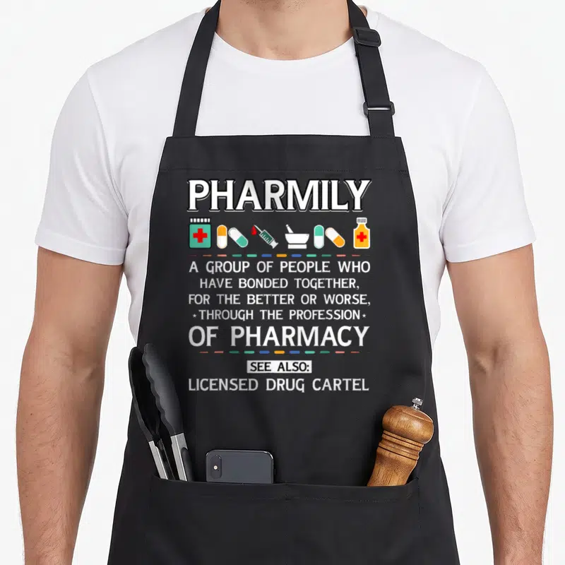 Pharmily pharmacist apron - PHARMILY text with pharmacy icons and Licensed Drug Cartel caption in teal orange blue — shown on a black cotton canvas apron against a white background