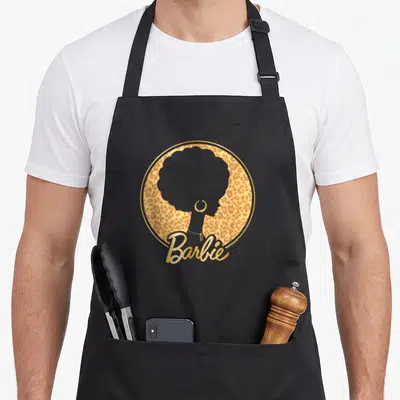 Afro leopard apron - Grey afro woman silhouette in gold leopard circle with Barbie script — shown on a black cotton canvas apron against a white background
