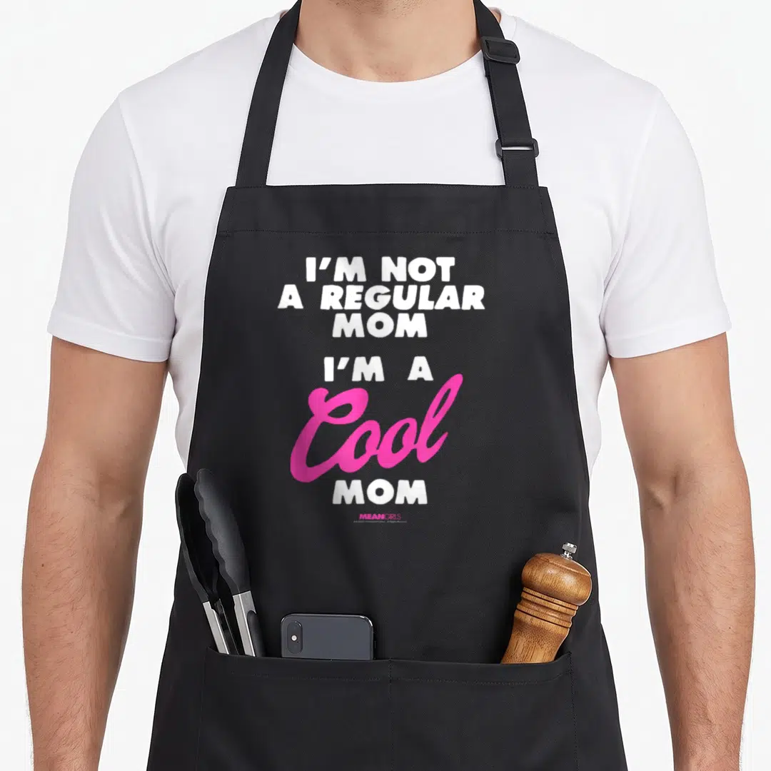 Y2k mean apron - Stacked white and pink text reading I'M NOT A REGULAR MOM I'M A Cool MOM — shown on a black cotton canvas apron against a white background