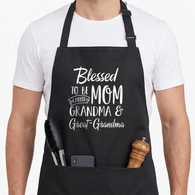 Called mother's day aprons - White stacked text reading Blessed to be called Mom Grandma Great-Grandma on black fabric — shown on a black cotton canvas apron against a white background
