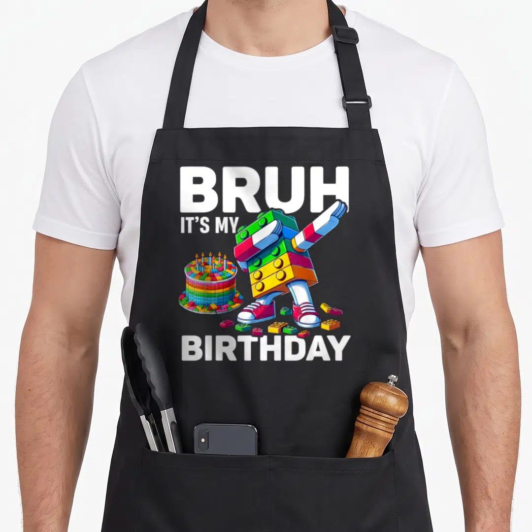 Bruh birthday block & apron - Dabbing block figure next to a brick cake with BRUH IT'S MY BIRTHDAY text — shown on a black cotton canvas apron against a white background