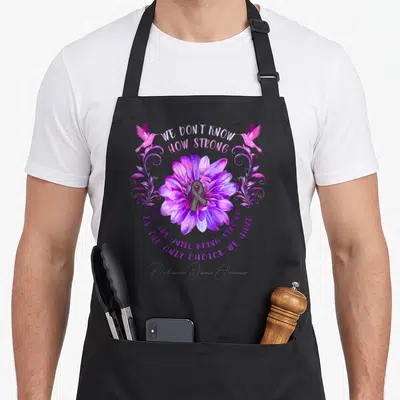 Flower parkinsons awareness apron - Purple flower with grey ribbon and two hummingbirds surrounding inspirational text — shown on a black cotton canvas apron against a white background