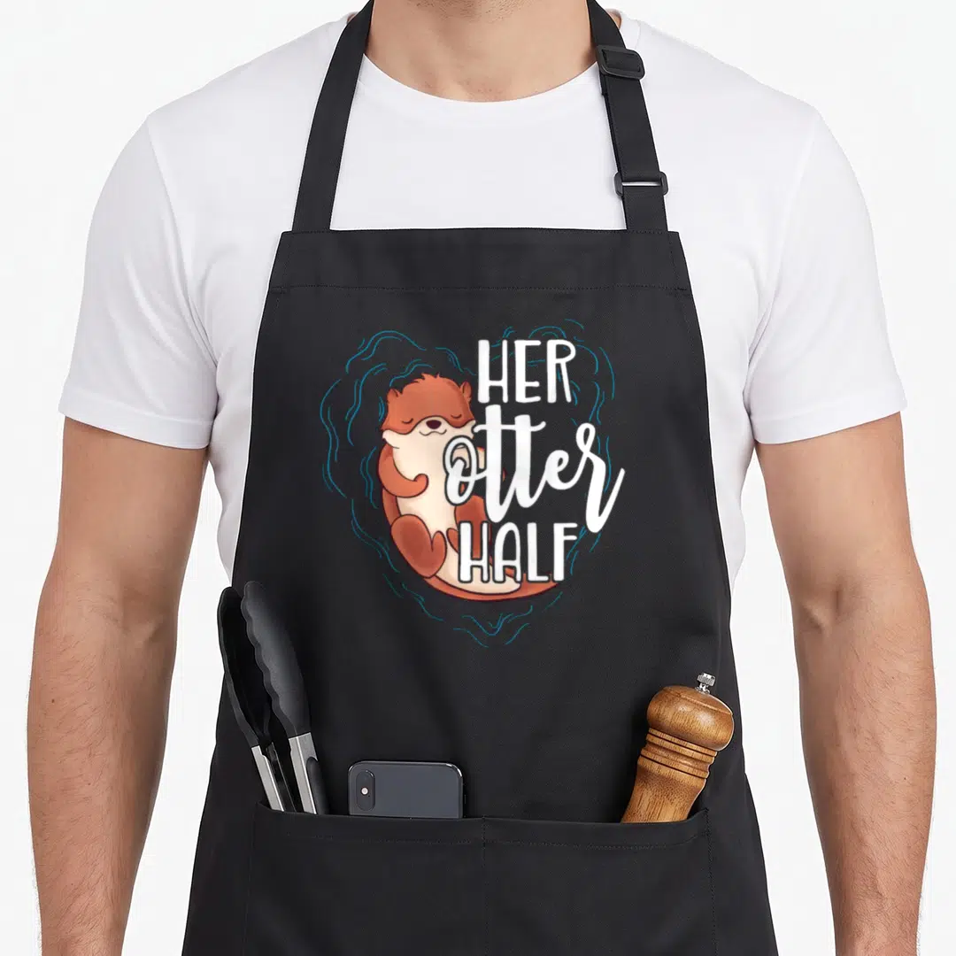 Otter valentine's day apron - Cartoon brown otter with blue swirl heart and white text HER OTTER HALF — shown on a black cotton canvas apron against a white background