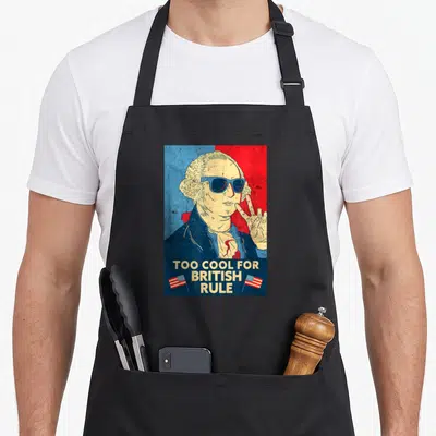 Rule george 4th of july apron - George Washington portrait sunglasses Too Cool For British Rule text two flags — shown on a black cotton canvas apron against a white background