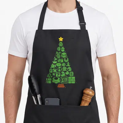Character christmas tree apron - Green game item tree with yellow star and red Super Mario text — shown on a black cotton canvas apron against a white background