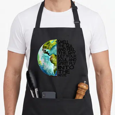 Smell sky apron - Watercolor half-globe in blue and green next to ten lines of black inspirational text — shown on a black cotton canvas apron against a white background