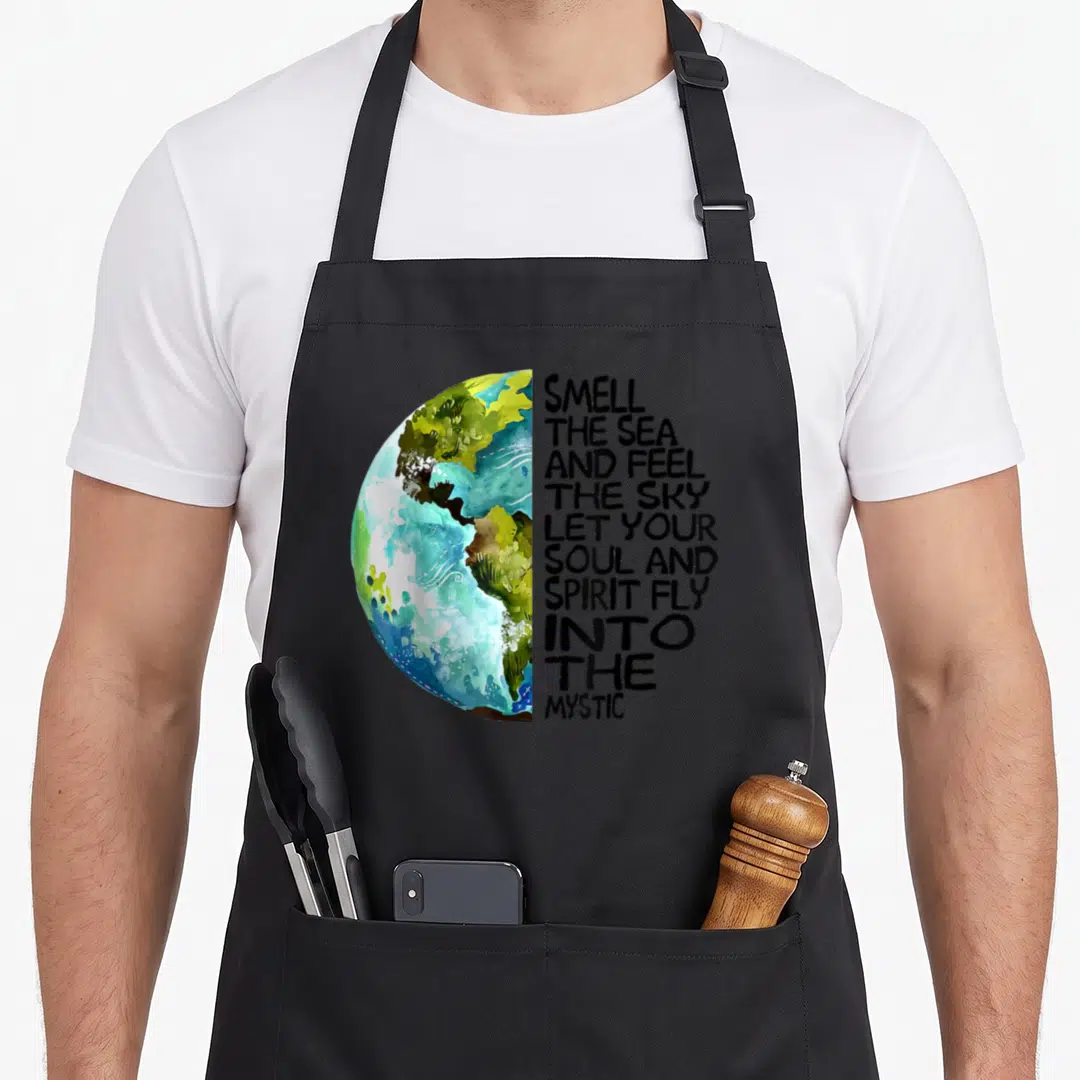 Smell sky apron - Watercolor half-globe in blue and green next to ten lines of black inspirational text — shown on a black cotton canvas apron against a white background