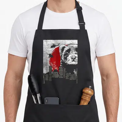 Weasel pet apron - Distressed panda head over red circle with helicopters and grey city skyline — shown on a black cotton canvas apron against a white background